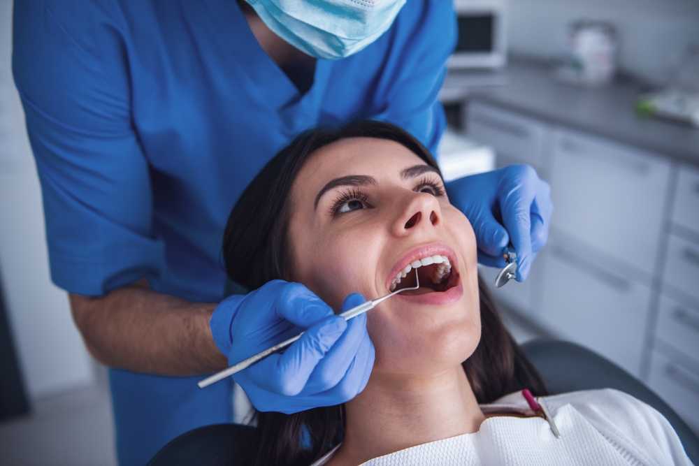 Dental professional carefully examining a patient’s teeth with specialized tools in a modern clinic, representing safe and expert oral surgery services in Cupertino - Cupertino Oral Surgery
