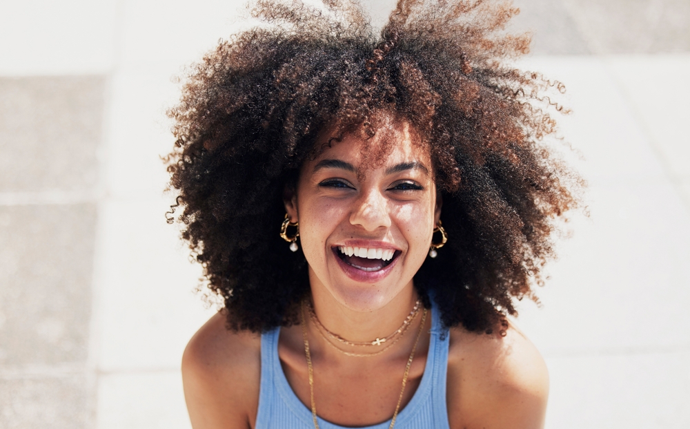 Portrait of a woman with a radiant smile and natural curls, highlighting the confidence that comes with healthy teeth and professional care at Cupertino Dental - Cupertino Dental